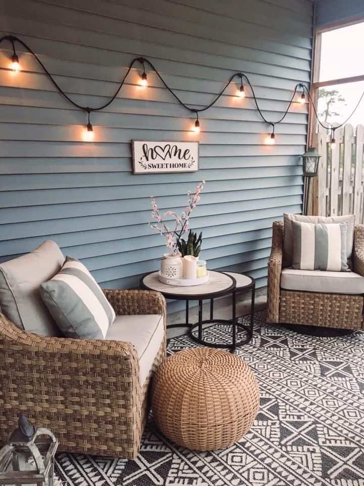 Front porch with rattan lounge chair, sunset‑orange pillows, and teal lanterns