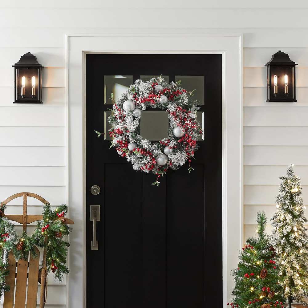 Modern front door with frosted silver ornament wreath catching warm exterior evening lights.