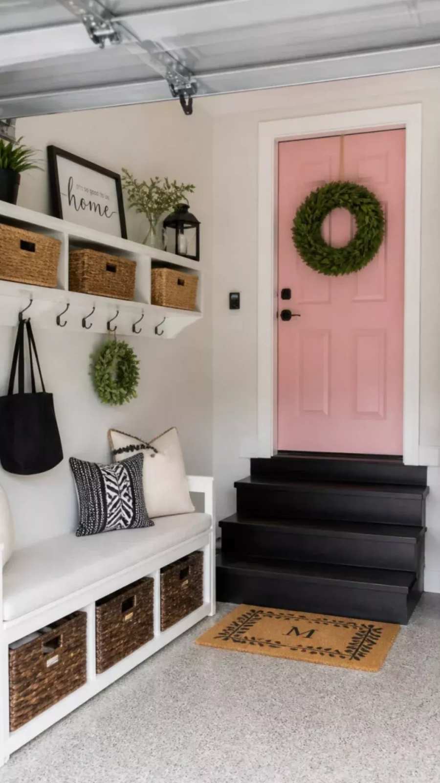 garage entry with pink painted door, built‑in drop zone, wicker baskets, warm lighting