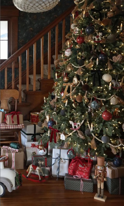 Christmas tree base with wrapped gifts, classic nutcracker, pine boughs, soft white lights.