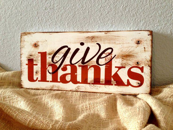 Dining room wall with a distressed red script sign, reclaimed wood table, linen napkins, warm pendant lighting.
