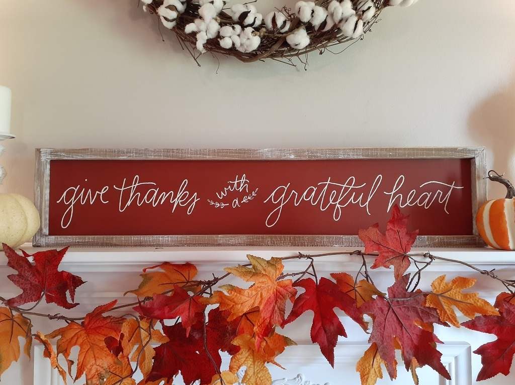 Fireplace mantel with a deep red heart‑shaped sign, copper accents, plush throw, warm candlelight.