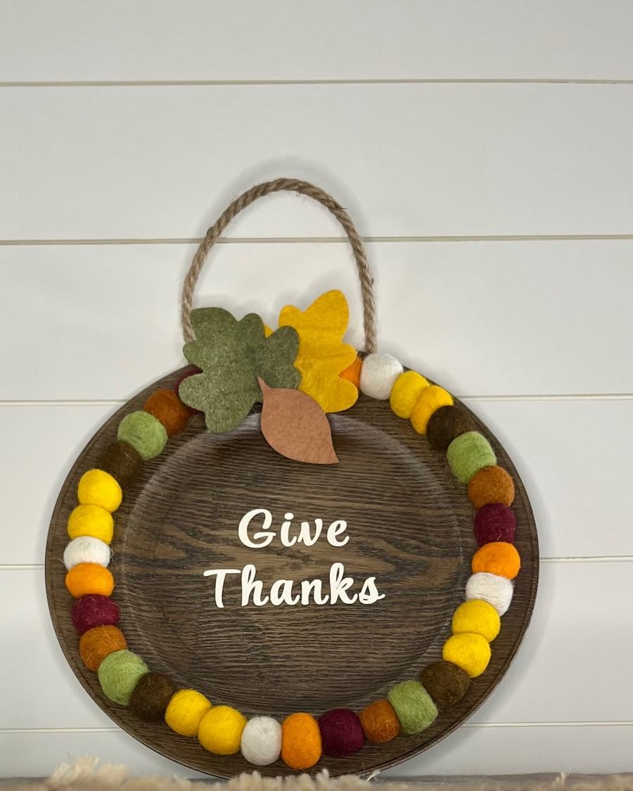 Kitchen wall, reclaimed wood plaque with “Give Thanks,” white shiplap, stainless steel pendant, marble countertop.
