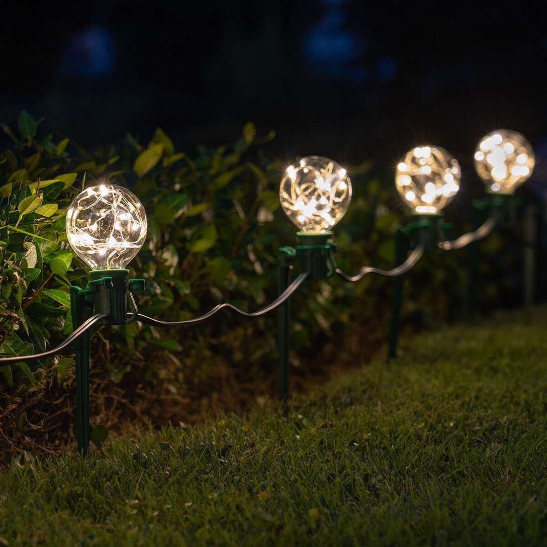 Pathway lined with modern, spherical globe lights as outdoor christmas decorations.
