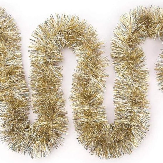 Thick gold tinsel garland wrapped around a tree branch with silver baubles in a bright living room.
