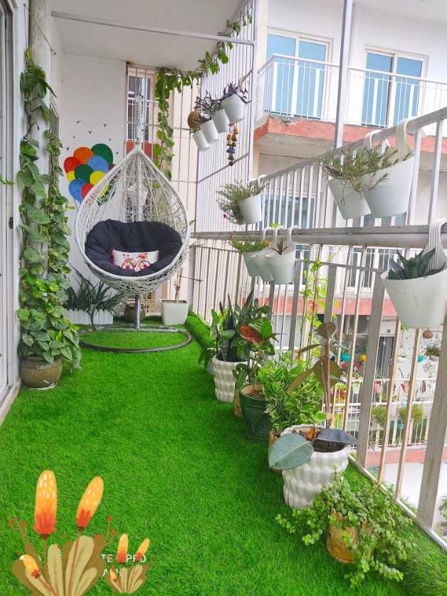 Green balcony garden with a white hanging teardrop swing, abundant foliage, and soft lighting.