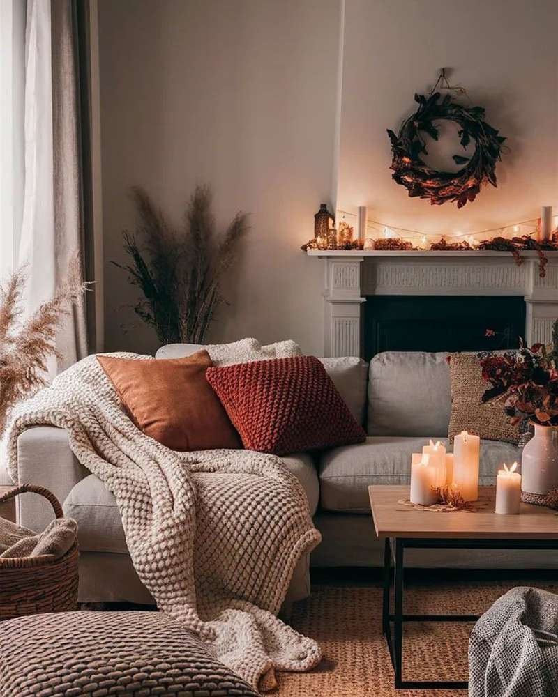 living room with grey sofa, chunky throw, candles, mantel wreath, soft lighting, muted tones
