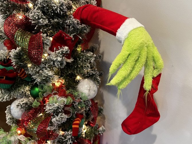 Tree with a Grinch arm holding a red stocking and green ornaments