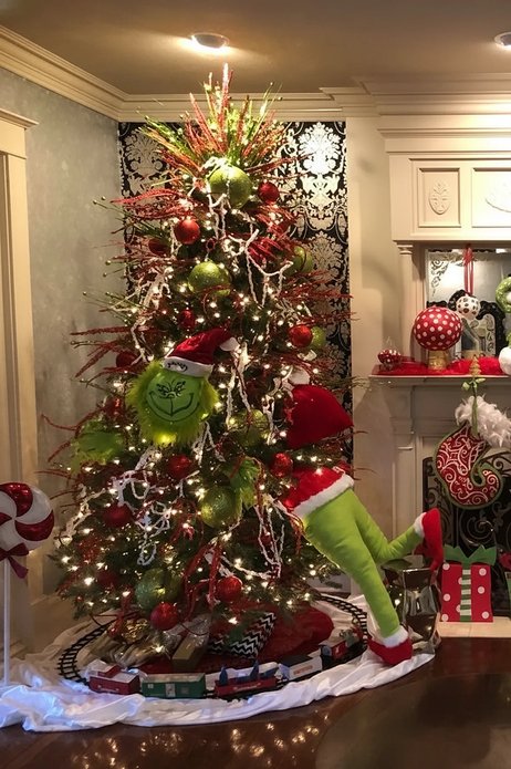 Tree with Grinch legs and a train ornament in a cozy room