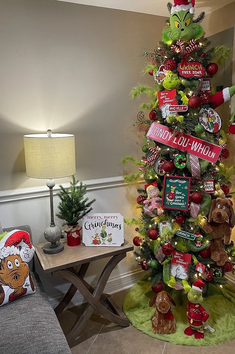 Tree with a Cindy Lou Who figure and green street sign in a cozy room