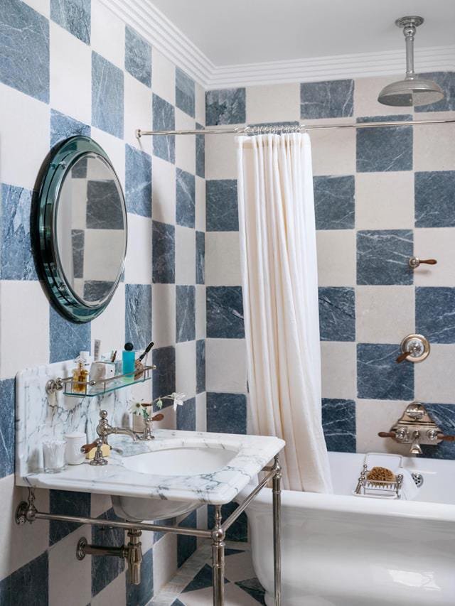 Guest bathroom with blue and white checkered tile shower enclosure and warm brushed nickel fixtures lighting.