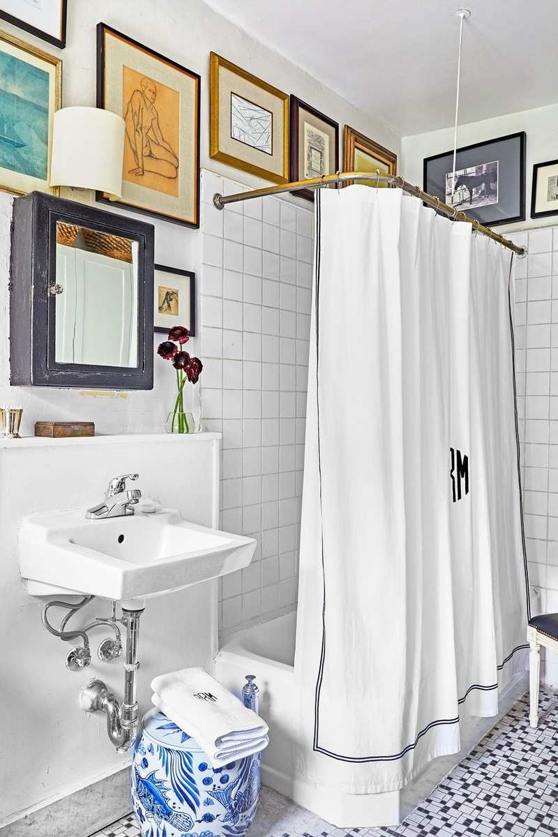 Guest bathroom showcasing custom curated picture gallery wall surrounding a white pedestal sink with warm sconces.
