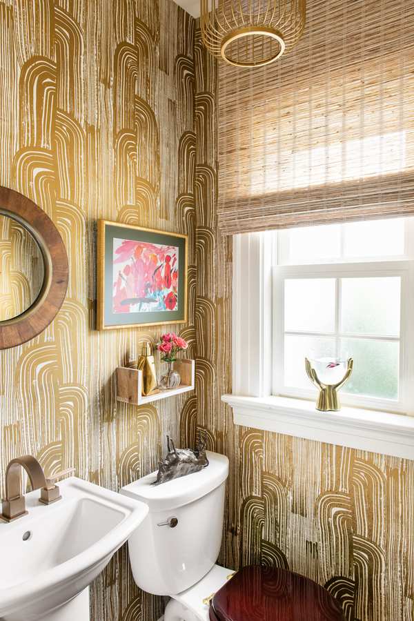 Guest bathroom featuring metallic gold foil geometric wallpaper, classic pedestal sink, and warm ambient wall lights.