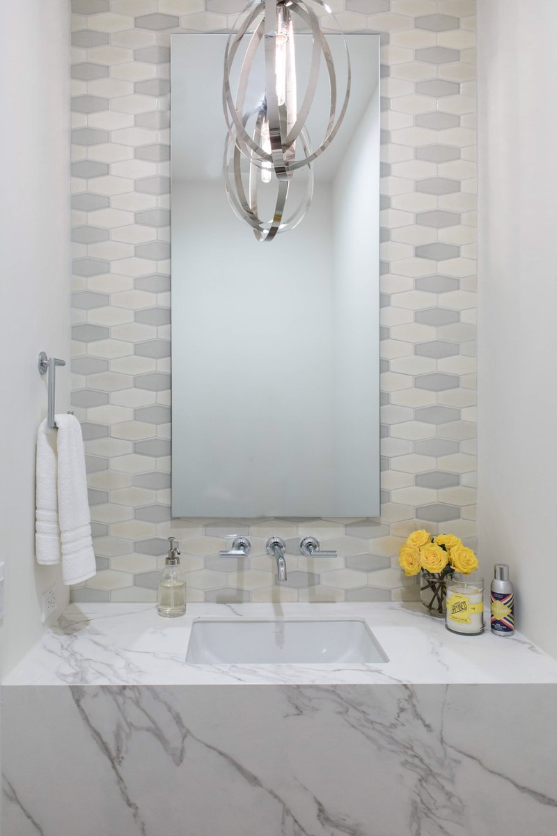Marble walk-in shower with a modern brass pendant light in a luxury guest bathroom.