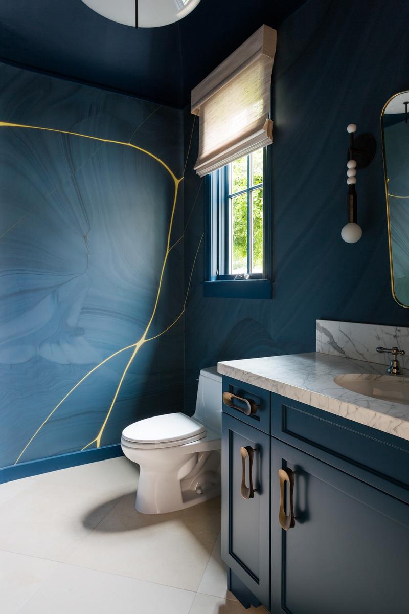 Guest bathroom featuring deep navy walls and a matching moody blue vanity cabinet.