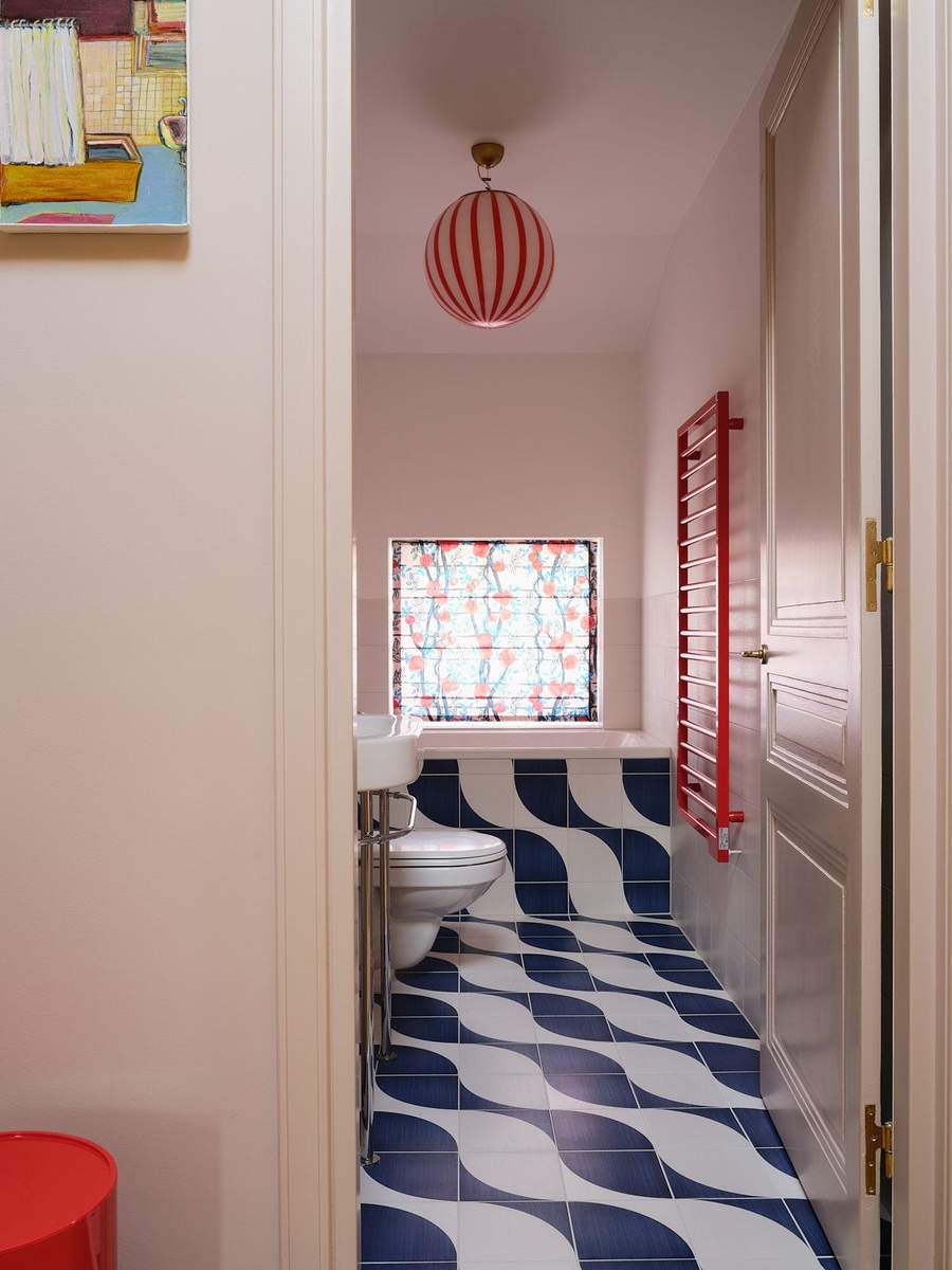 Guest bathroom with a striking red pendant light and unique wavy patterned floor tiles.