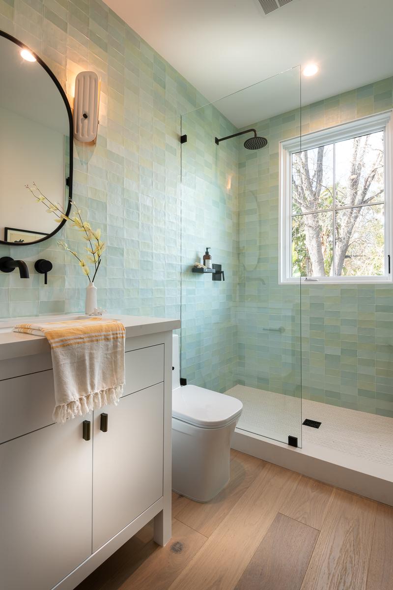 Guest bathroom shower featuring soothing sage green subway tiles and natural light.