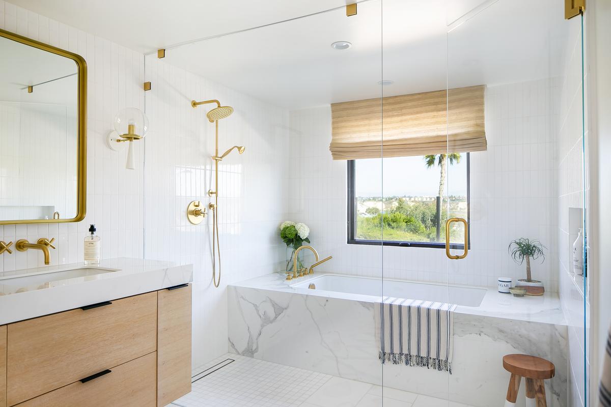 Modern guest bathroom vanity featuring white marble, gold hardware, and natural wood cabinetry.
