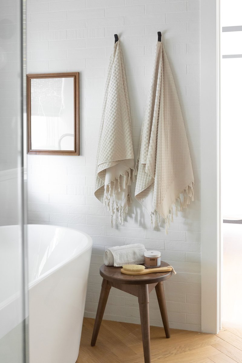 A bright guest bathroom focused on a white soaking tub styled with fluffy towels.