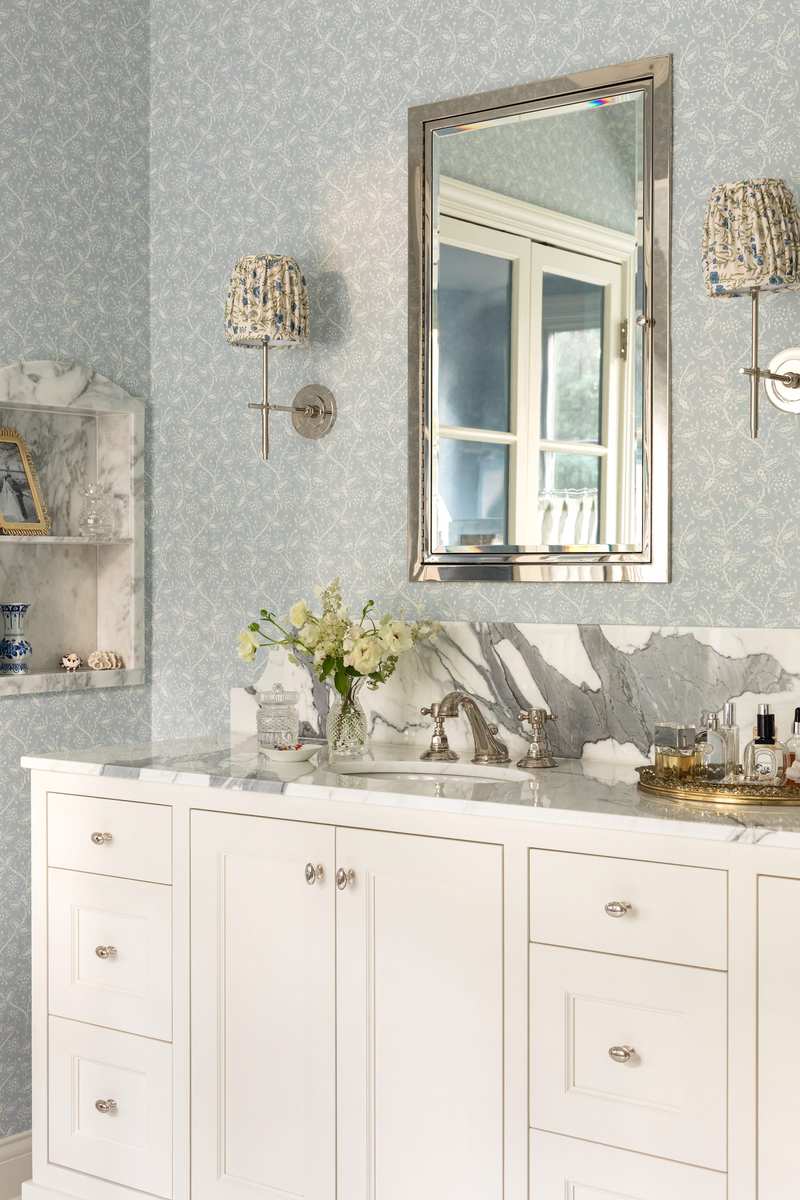 Guest bathroom with a bright white vanity, stylish wallpaper, and elegant wall sconces.
