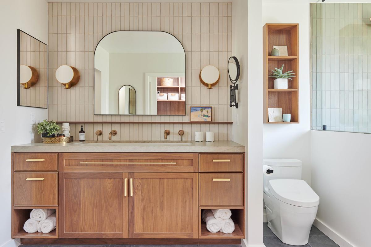 Close-up of a warm wood double vanity with marble countertops and modern hardware.