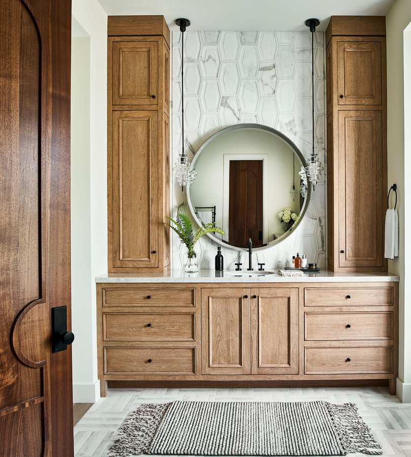 Guest bathroom with a rustic-modern wood vanity and a stylish round mirror above.