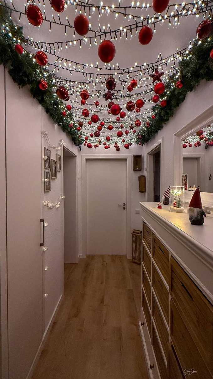 Hallway ceiling featuring red glass baubles suspended from thin fishing line, illuminated by soft LED uplighting.