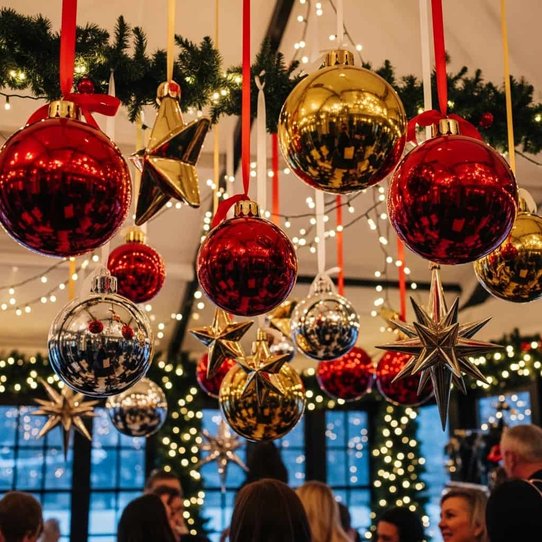 Open living space with suspended red and gold glass baubles, sheer ribbons, and soft downlights