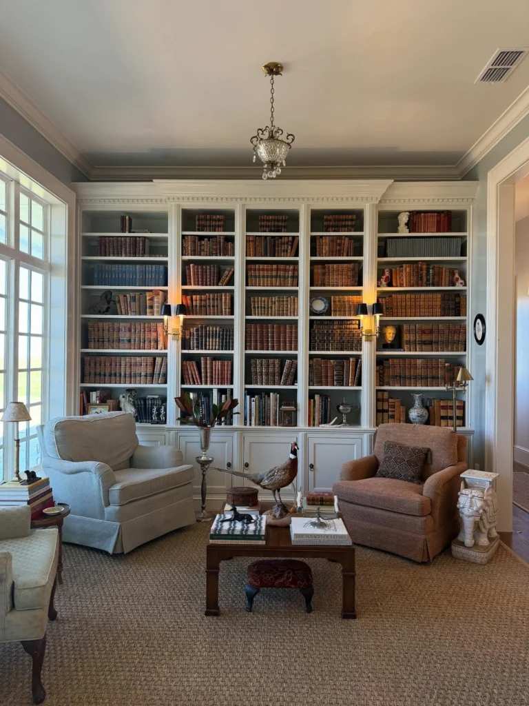 Home library with a white built-in bookcase wall and two armchairs for a clean, bright feel.