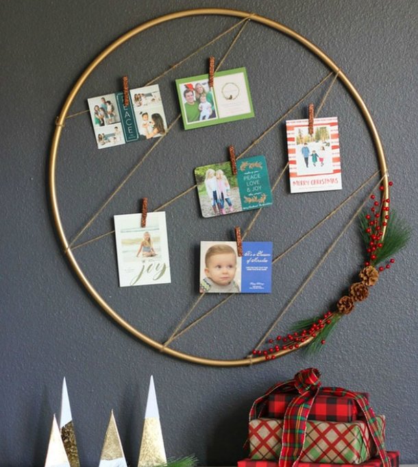 Large circular gold metal hoop adorned with greenery and cards hanging on living room wall