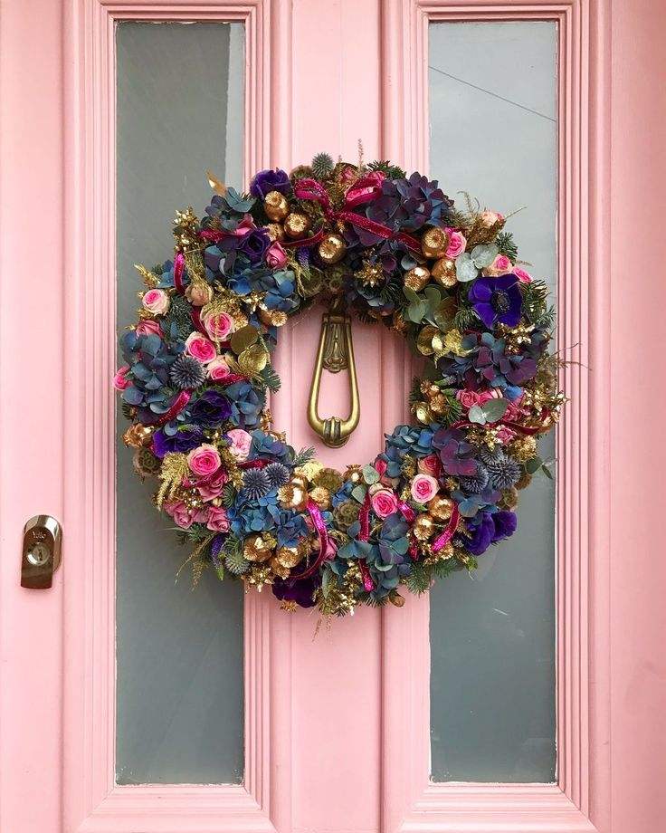 Sophisticated front entrance with jewel-toned hydrangea and rose holiday wreath under warm porch light.