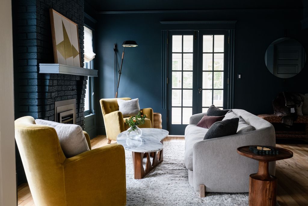 Cozy small living room with cream bouclé accent chair, brass sconce, woven rug.