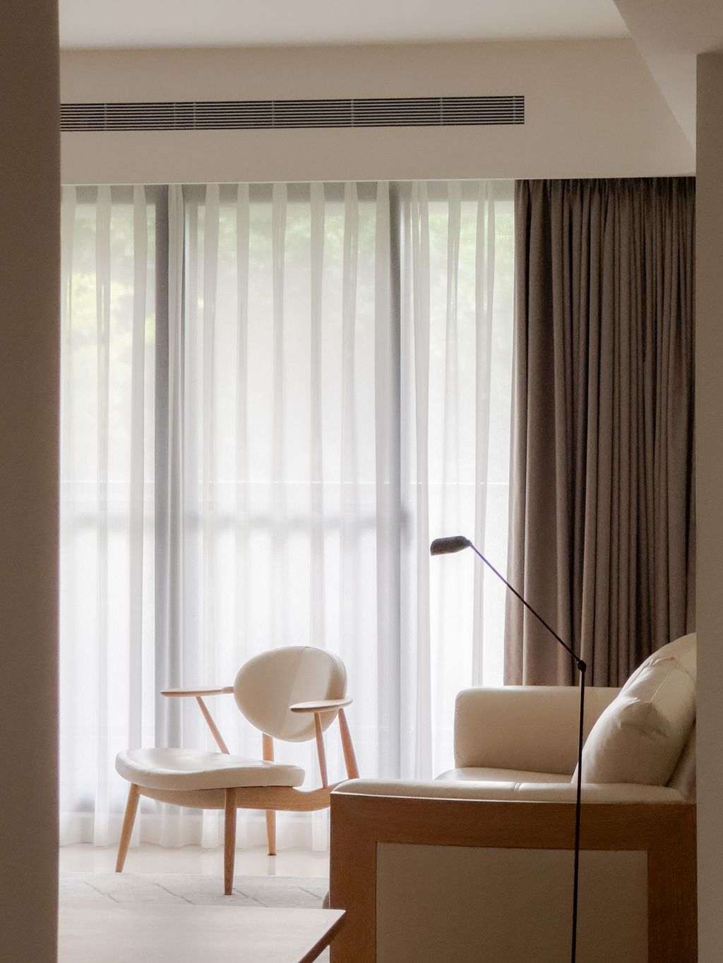 Vertical gallery wall frame setup above a sleek gray sofa with soft floor lamp.