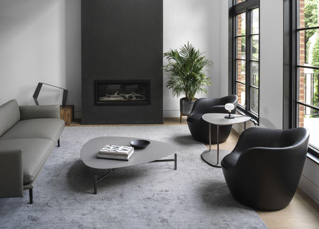 Small living room featuring soft curved cream sofa and round upholstered pouf ottoman.