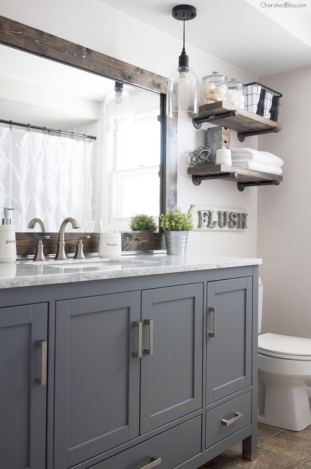 Bathroom combining black pipe shelving, reclaimed wood mirror frame, barn‑door style vanity, and concrete floor.