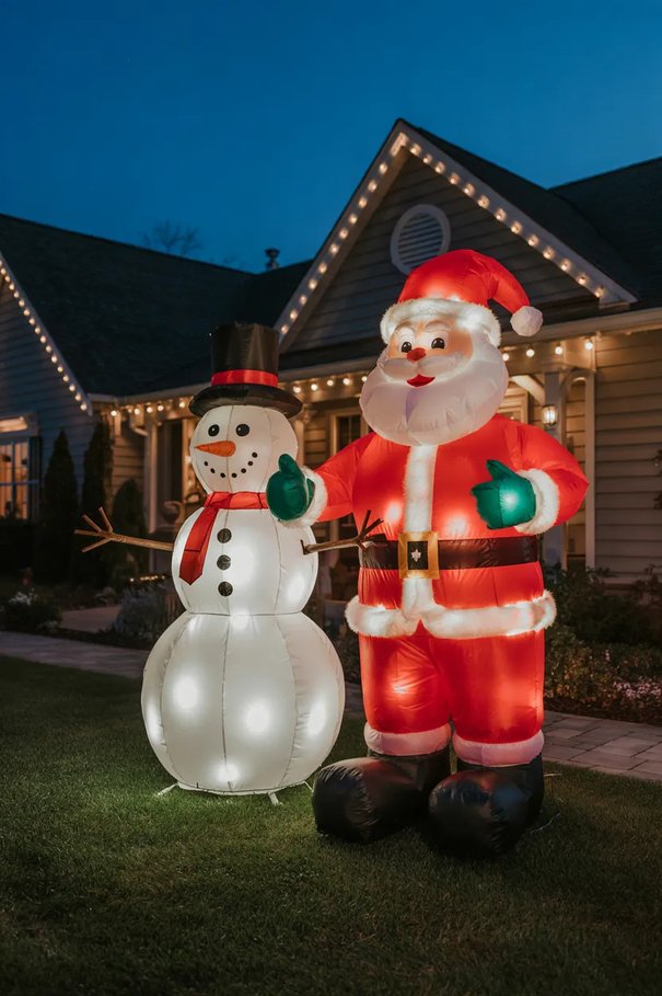 Front yard lawn featuring festive nylon inflatables with warm internal LED lights and evergreen accents.