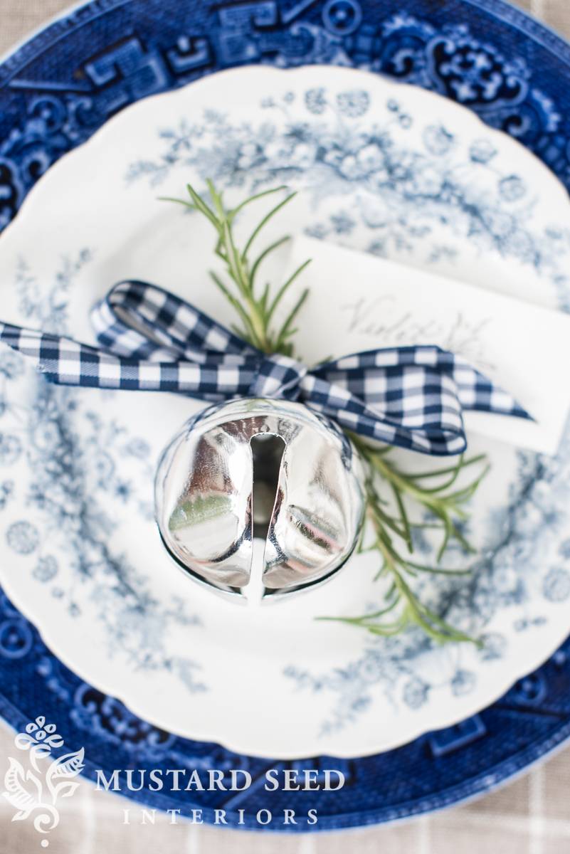 Dining room table setting with wooden dining table, linen napkins, rattan bell napkin rings, candlelight.