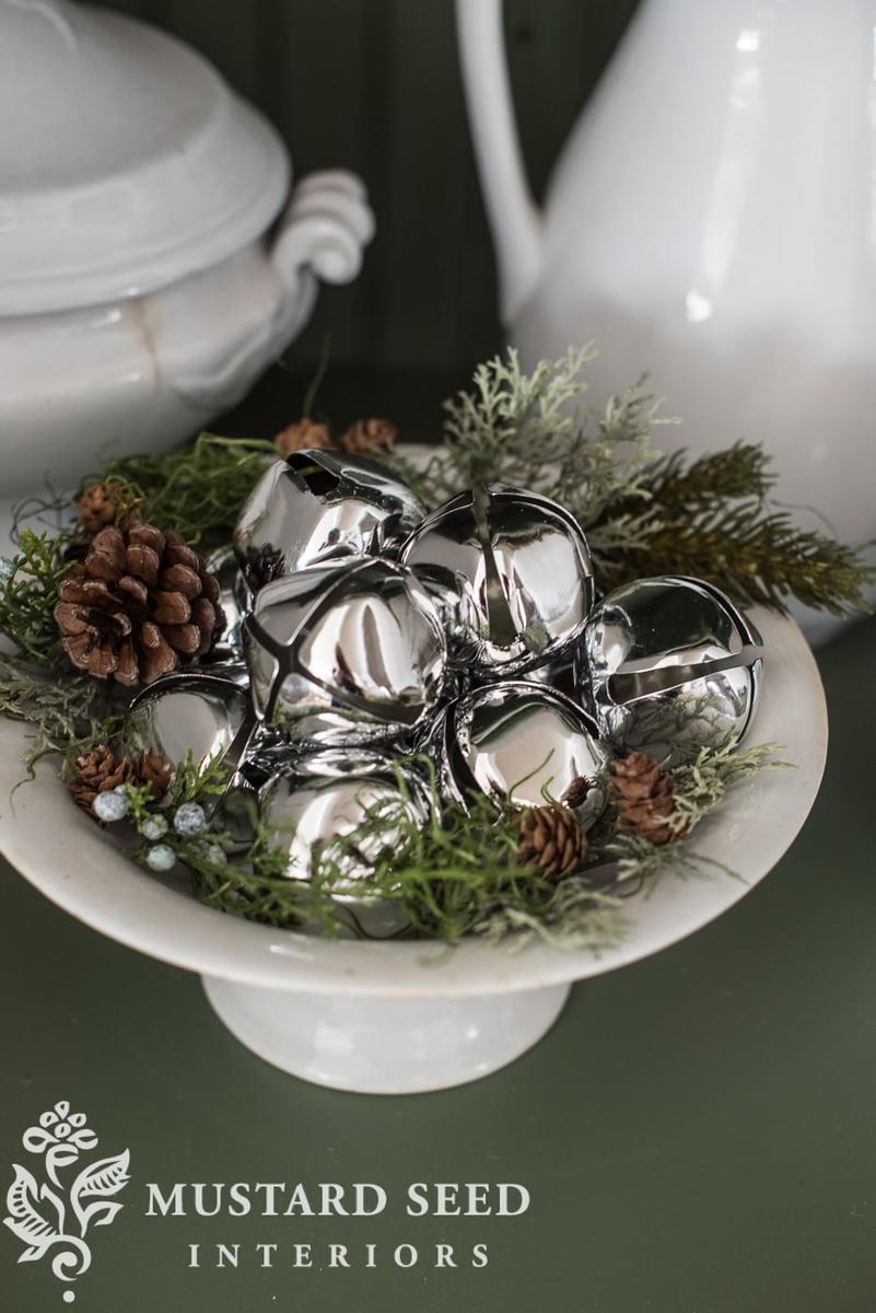 Modern foyer console table with round mirror, eucalyptus copper bell wreath, warm brass lamps.
