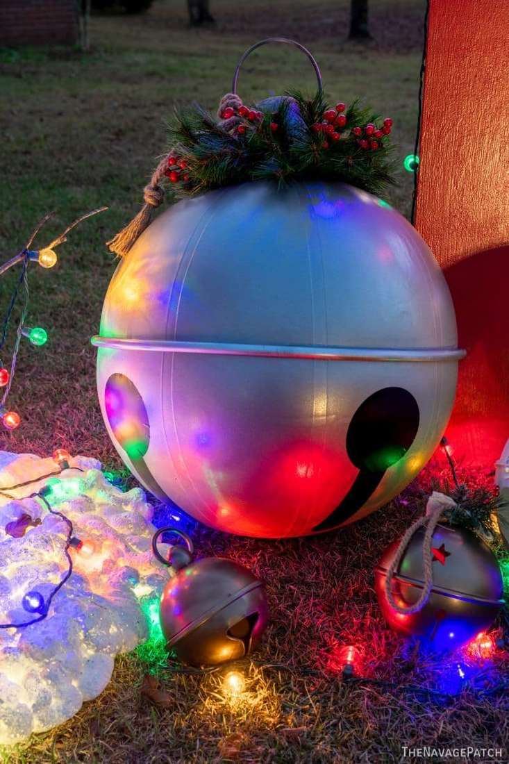Large metallic red and gold jingle bells displayed as outdoor christmas decorations on porch steps.