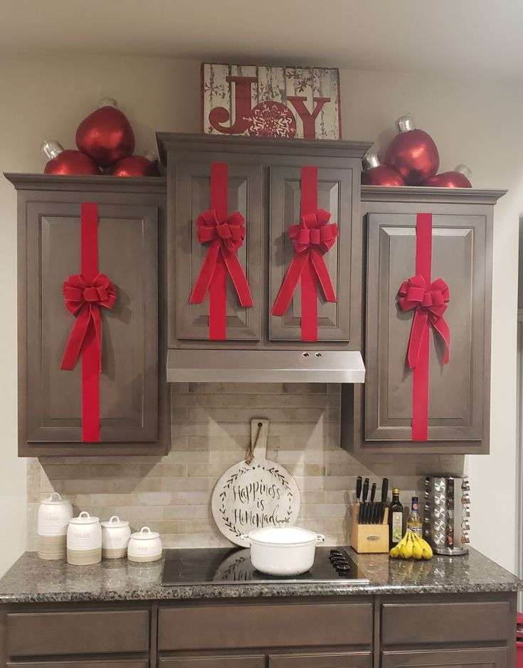 Kitchen cabinets adorned with oversized red satin bows, positioned on each door handle area.
