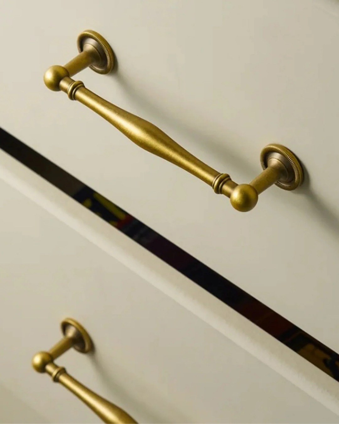 Deep gray cabinets paired with thin, elegant brass bar pulls in a modern kitchen.