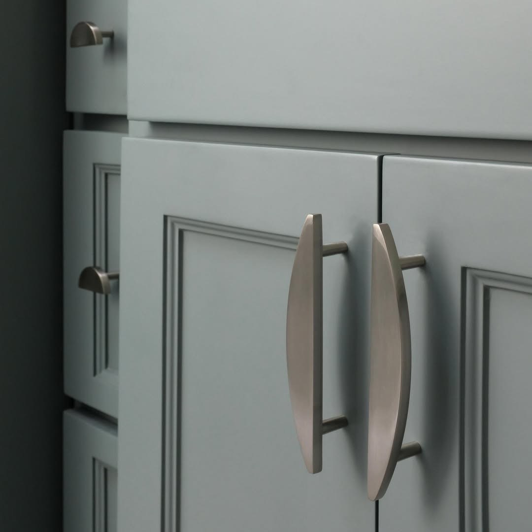 Light gray cabinets with long brushed nickel bar pulls in a bright modern kitchen.