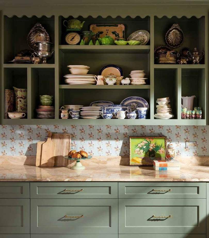 Decorative green kitchen hutch with gold brass knobs in a bright home interior.