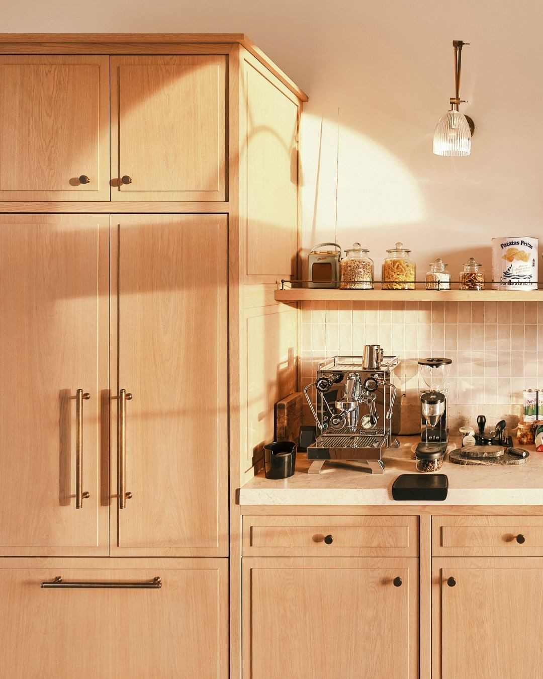 Light oak kitchen cabinets with brushed brass pulls in a natural, airy home.