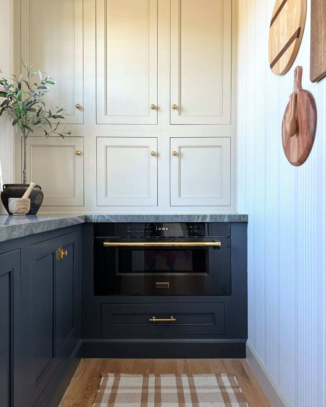 Classic navy blue kitchen cabinets with polished brass hardware in a luxury home.
