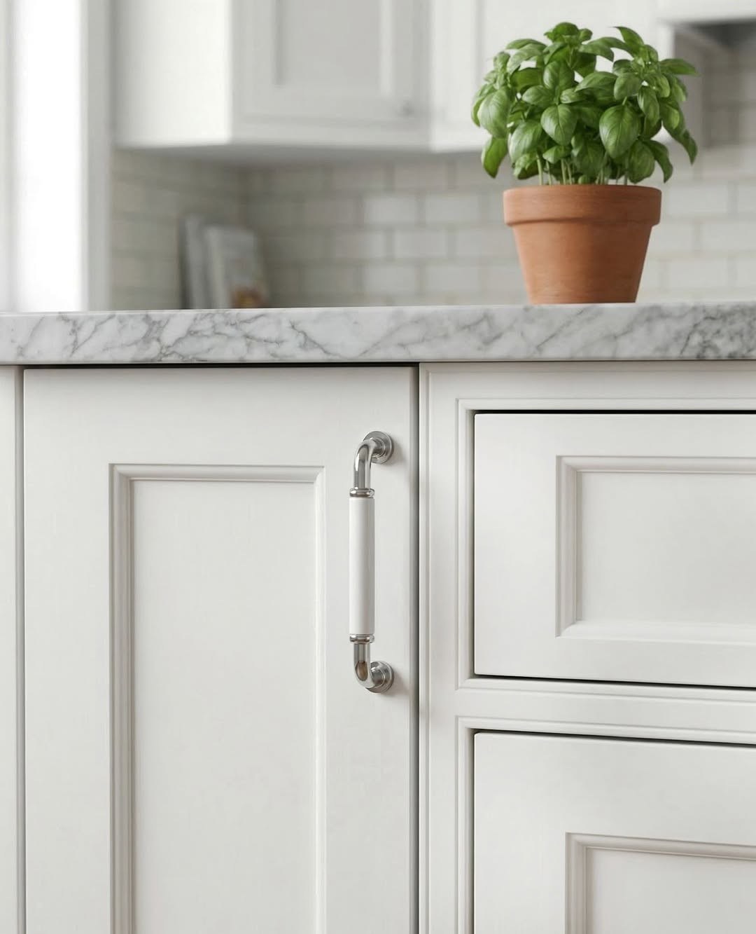 Fresh white kitchen cabinets styled with reflective polished chrome knobs.