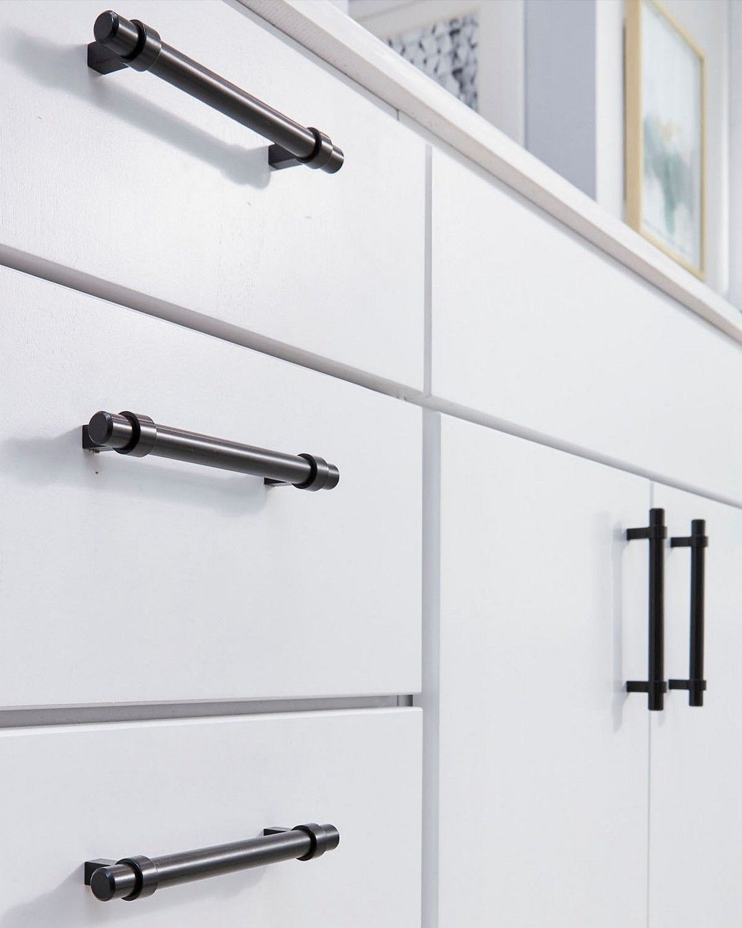 Modern white kitchen drawers featuring sharp matte black long bar pulls.