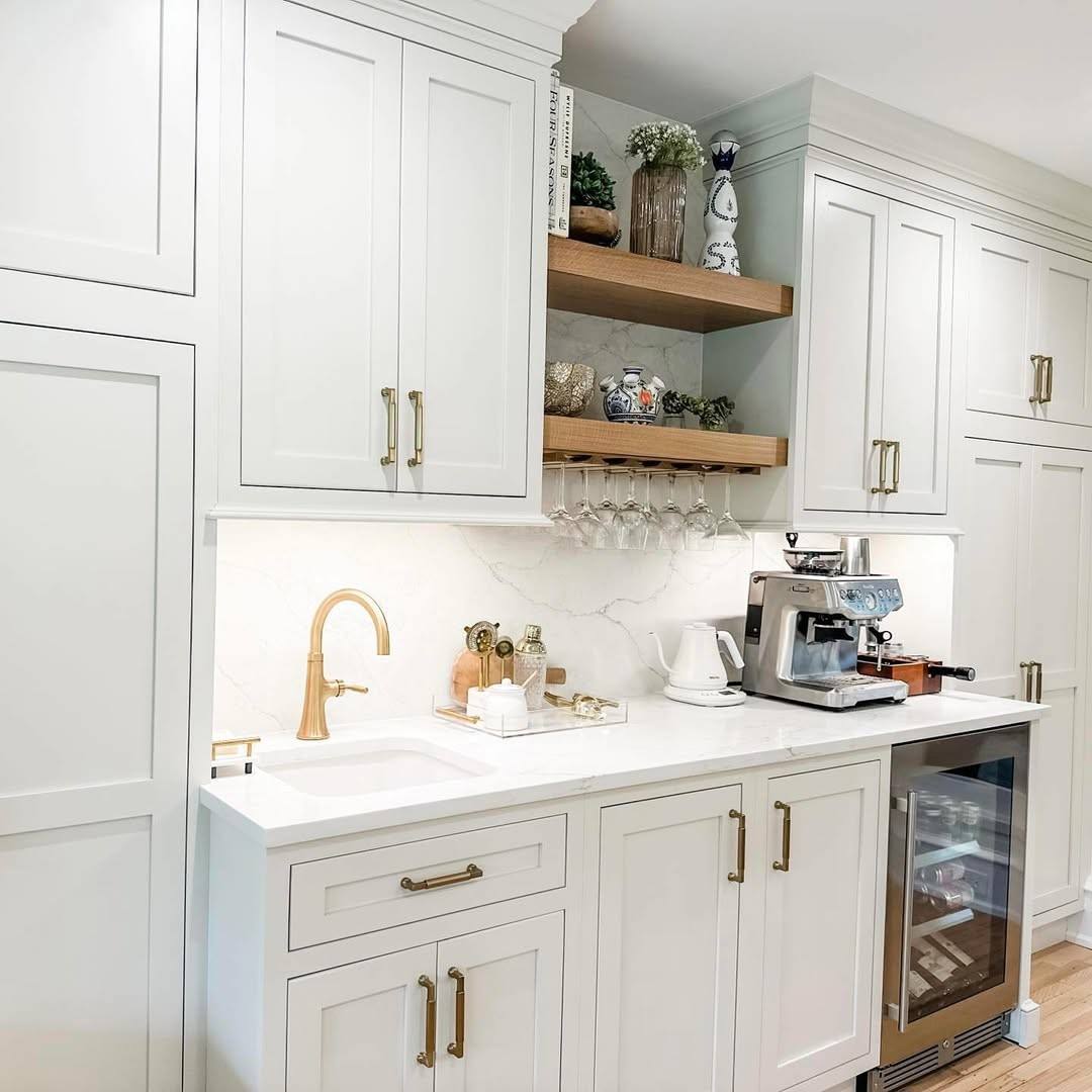 An all-white kitchen with brass knobs on cabinets and an island focal point.