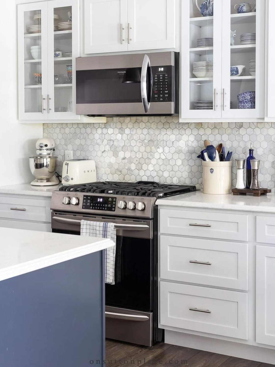 A modern white kitchen with sleek gold brass pulls installed on cabinets.