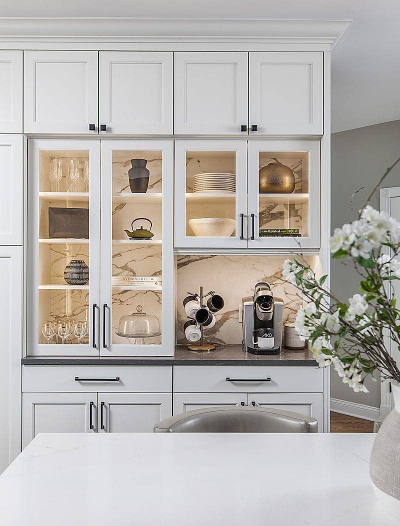 Kitchen with dark gray cabinets, concrete floors, and iron pendant lights.
